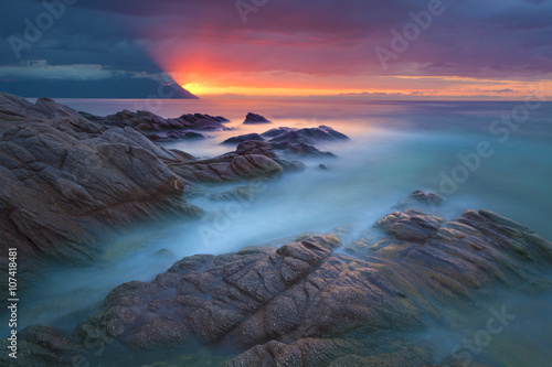 Waves and rocks in motion blur on coastline at dawn