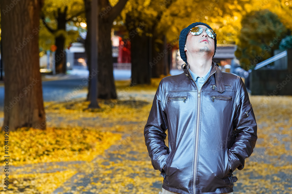 An asian man in a brown jacket walks in a street An asian man in a brown jacket walks in a street