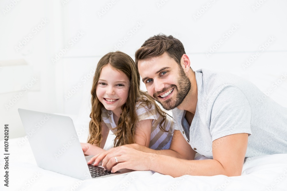 Happy father and daughter using laptop on bed Happy father and daughter using laptop on bed