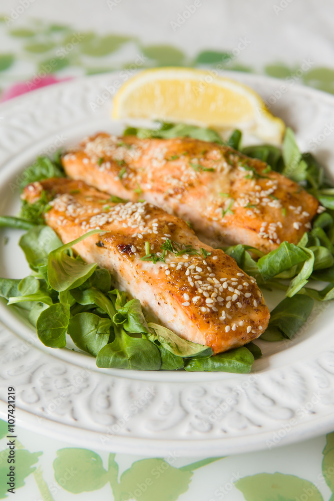 White plate with grilled salmon served with mini spinach and a piece of lemon. Healthy food for family. Home made dinner. Vegetarian lunch for diet.