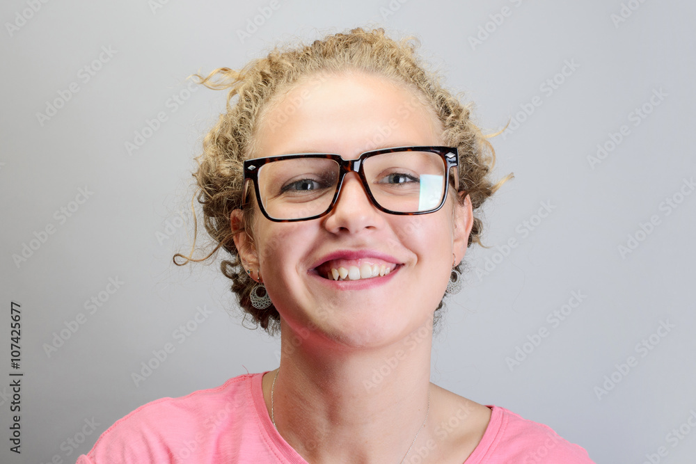 Smiling woman in glasses standing over gray background Smiling woman in glasses standing over gray background