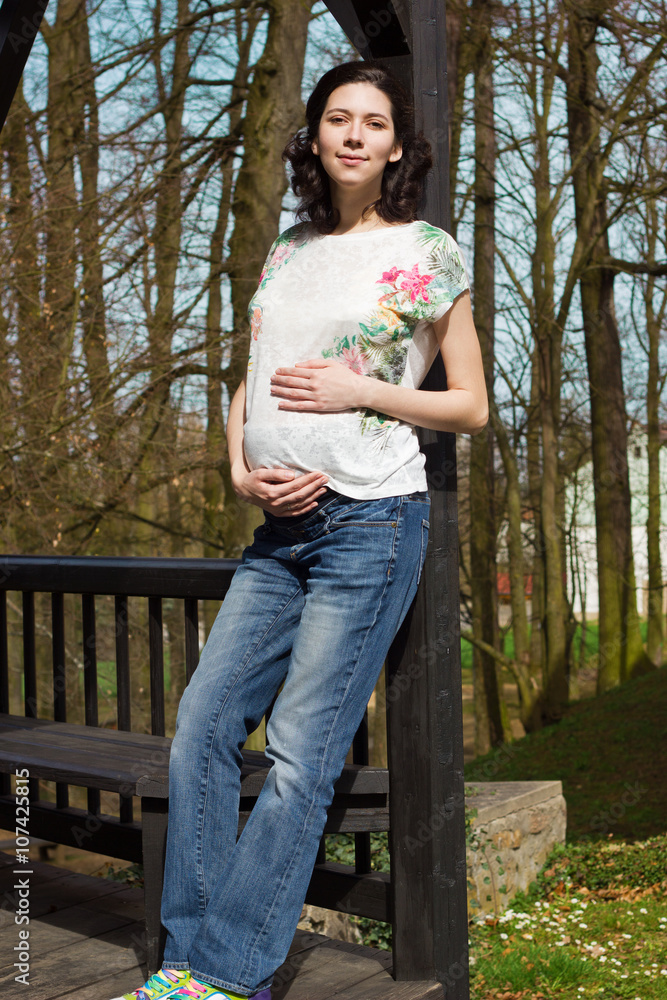 Beautiful pregnant woman in casual clothes walking in the park. Beautiful pregnant woman in casual clothes walking in the park.