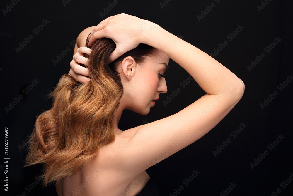 Fototapeta premium Układanie włosów.Portret kobiety z pięknymi długimi włosami na czarnym tle