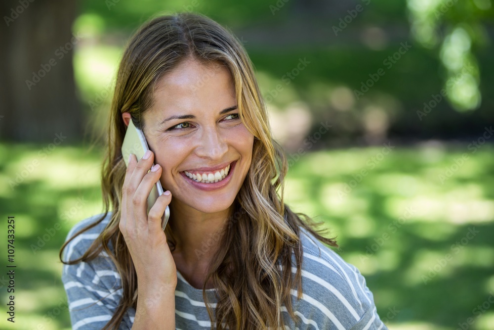 Smiling woman making a phone call in a park Smiling woman making a phone call in a park