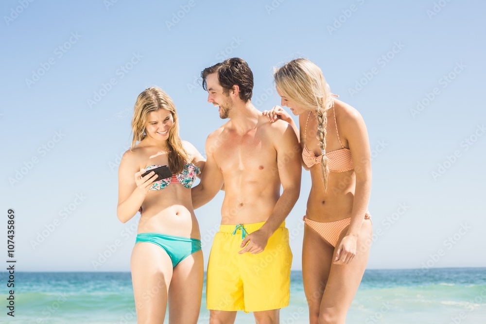 Young friends looking at mobile phone on the beach