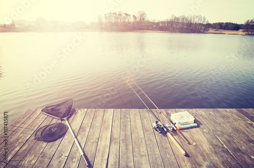 Vintage toned fishing equipment on a wooden pier at sunset.