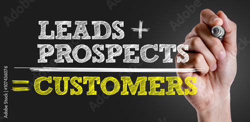 Hand writing the text: Leads + Prospects = Customers photo