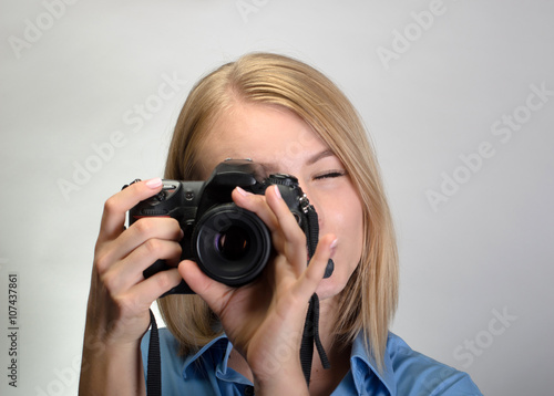 Young pretty woman with digital camera on gray background