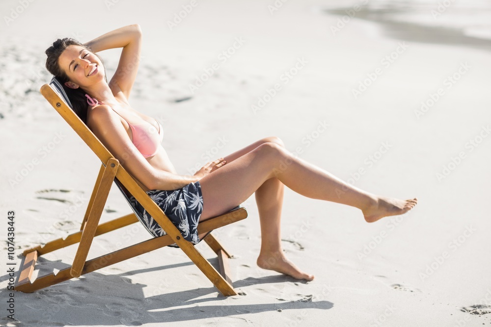 Happy woman sitting on an armchair on the beach Happy woman sitting on an armchair on the beach