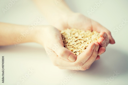 close up of woman hands holding oatmeal flakes