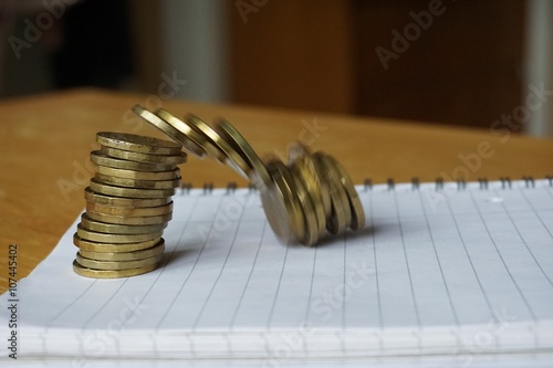 Money background of falling pile of coins made of gold and gilt metal on the paper notepad as a symbol of financial deterioration photo