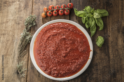Foto orizzontale di Piatto di sugo con ingredienti quali pomodorini e basilico su tavolo di legno photo