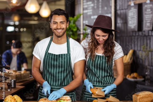Canvas Print Smiling baristas preparing sandwiches
