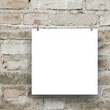 Close-up of one square blank frame hanged by pegs against grey weathered brick wall background