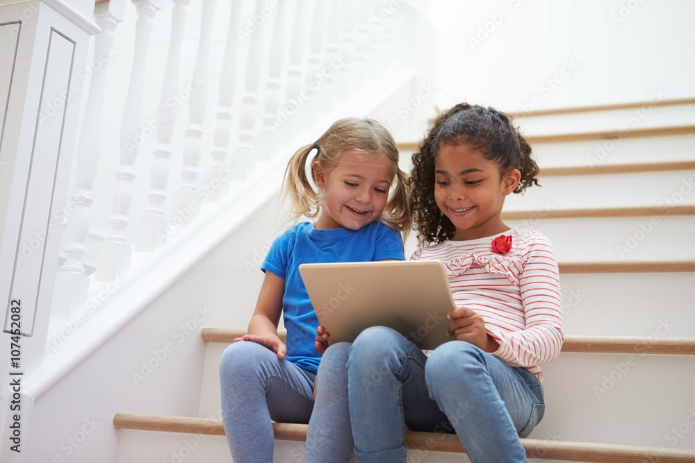 Two Girls Sitting On Staircase Using Digital Tablet