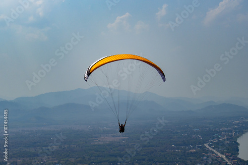 silhouette human is parachuting from the top of mountian