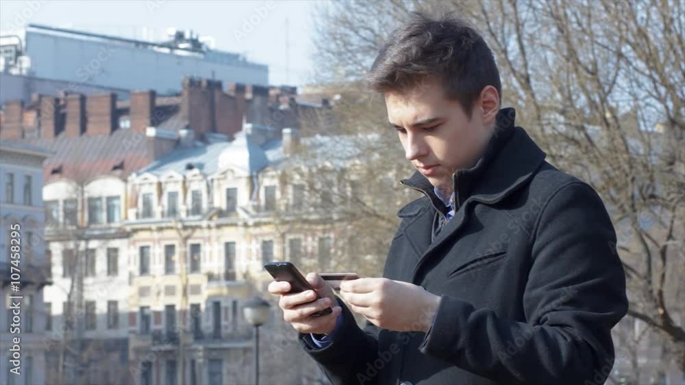 Man shopping online using phone and credit card outside
Man shopping online using phone and credit card outside