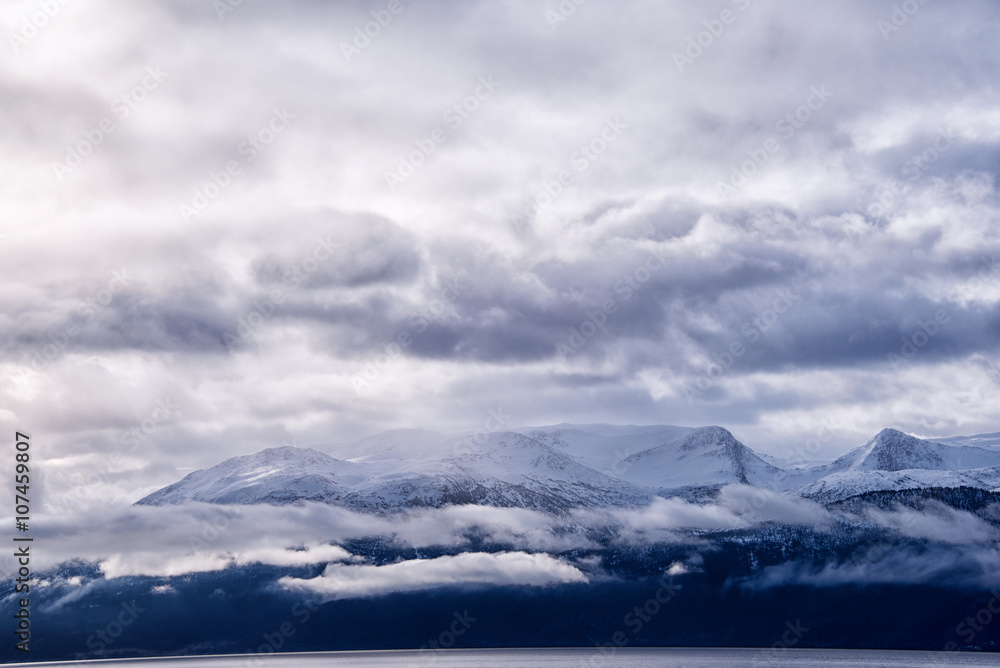 Amazing view of snow caped mountain range with storm clouds in the sky