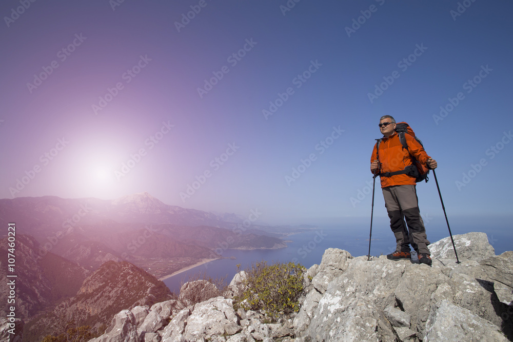 A traveler stands on top of a mountain and looks out to sea.