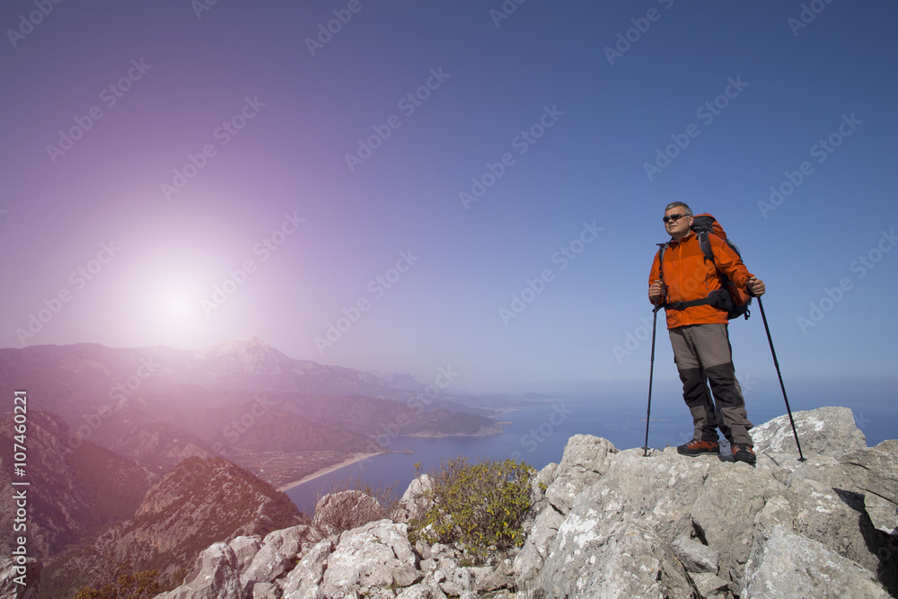 A traveler stands on top of a mountain and looks out to sea. A traveler stands on top of a mountain and looks out to sea.
