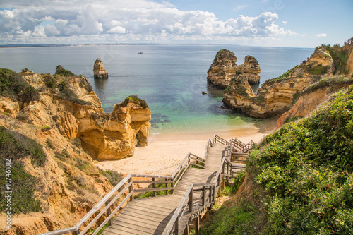 einsame hölzerne Treppe führt zu einem paradiesischen einsamen Sandstrand an der Algarve, Portugal