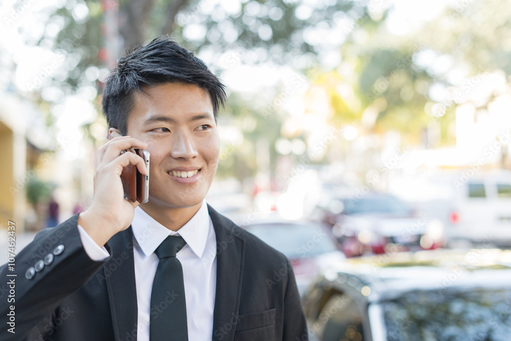 Korean businessman talking on cell phone outdoors Korean businessman talking on cell phone outdoors