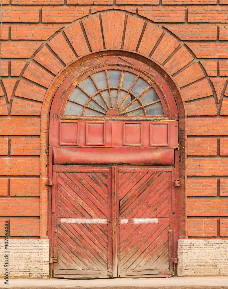 Old wooden gate on a brick facade of the administrative building. Old wooden gate on a brick facade of the administrative building.