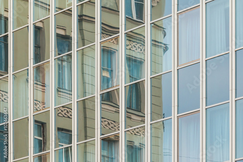 фотографія Specular facade of office building with reflection of an old building facade