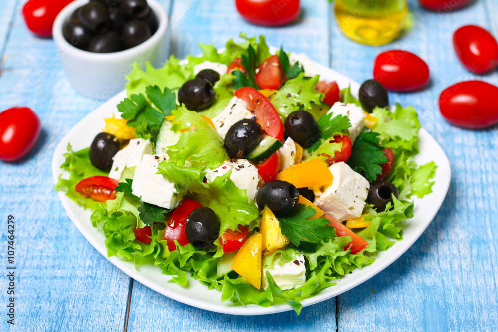 Greek salad with fresh vegetables, feta cheese and black olives on a wooden background