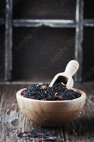 Delicious black tea with petals on the wooden table