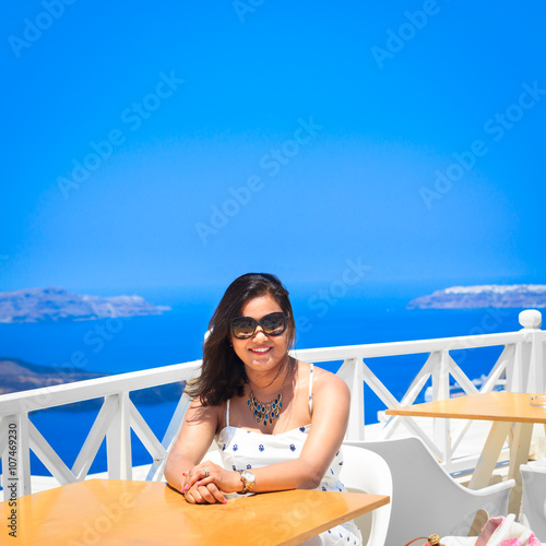 A women sitting happily enjoying summer in a hillside vineyard in  Santorini Greece