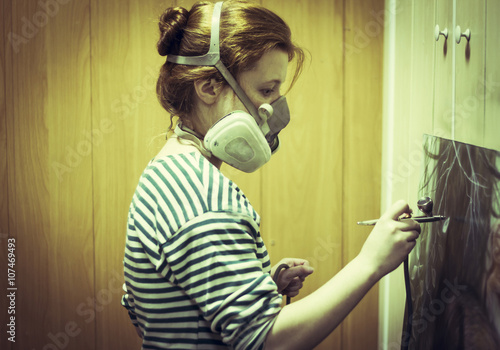 Artist in gas mask airbrushing painting in studio photo