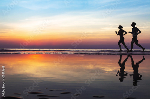 Fototapet two runners on the beach, silhouette of people jogging at sunset, healthy lifest