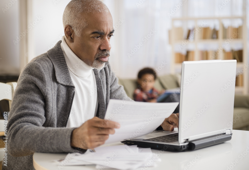 Mixed race man paying bills on laptop Mixed race man paying bills on laptop
