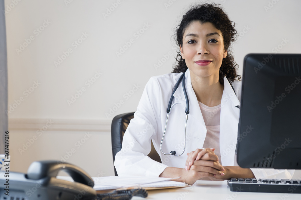 © JGI/Jamie Grill/Blend Images - Mixed race doctor sitting at desk in office