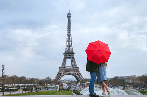 honeymoon in Paris, couple kissing behind red umbrella against Eiffel tower © Song_about_summer
