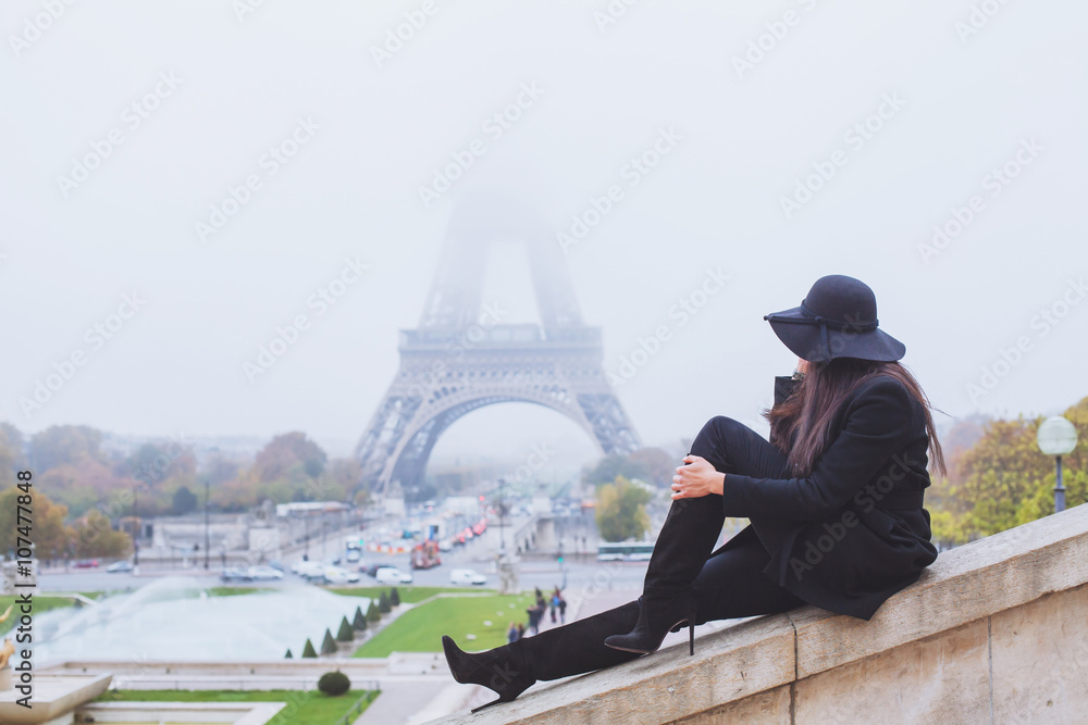 autumn and winter in Paris, fashion woman looking at Eiffel Tower in foggy day, France