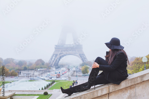 Photography autumn and winter in Paris, fashion woman looking at Eiffel Tower in foggy day,