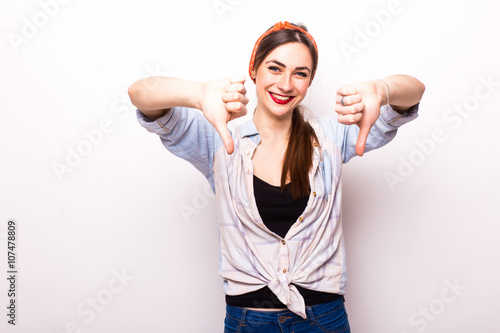 Happy smiling beautiful young woman showing thumbs down gesture, isolated over white background photo