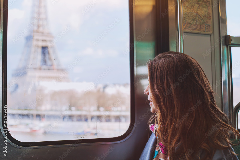 Fototapeta premium tourist looking to the Eiffel Tower through the window of metro in Paris, smiling girl visiting France