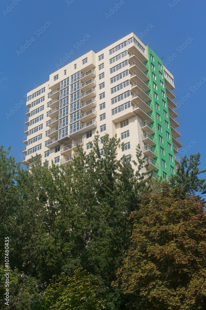 Facade of multistory buildings and green trees. Building