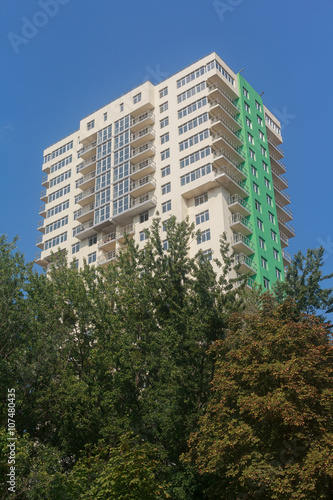 Facade of multistory buildings and green trees. Building