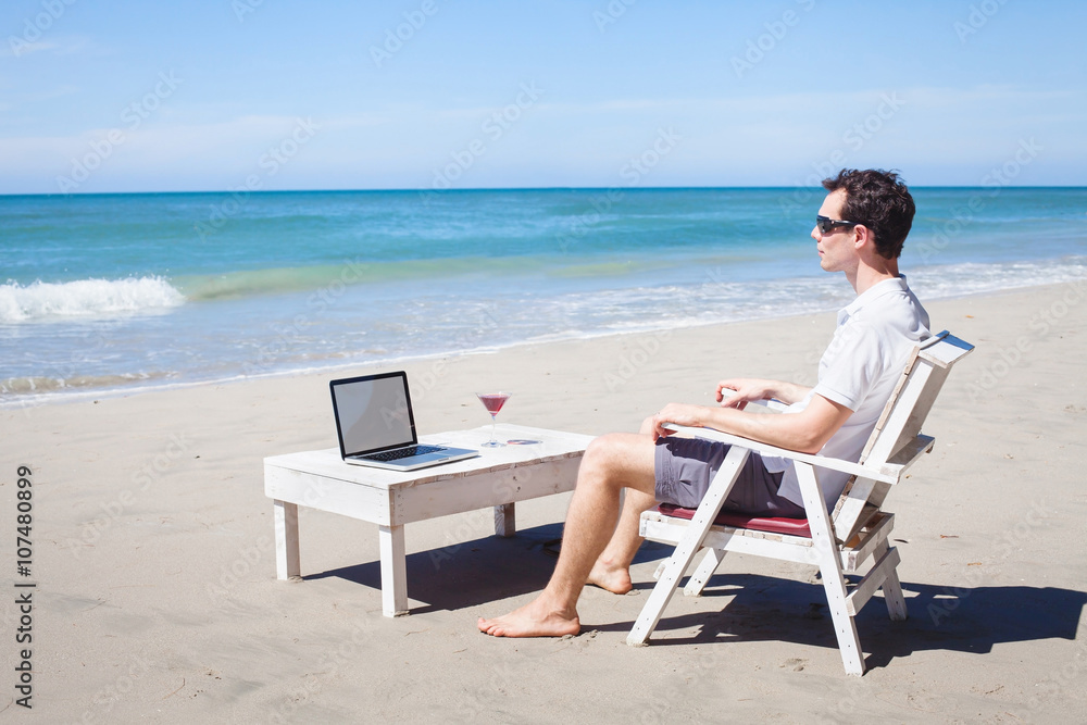 telecommuting, businessman relaxing on the beach with laptop and cocktail, freelancer workplace, dream job