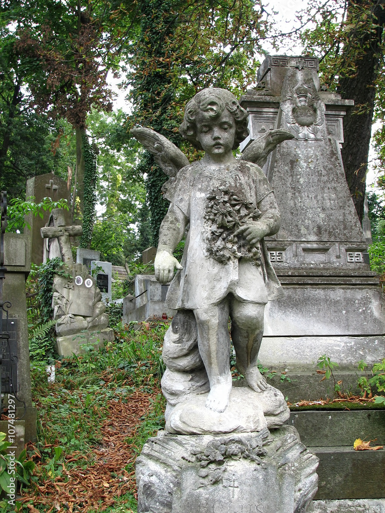 ancient stone sculpture little girl-angel with wings she  is holding a wreath of poppies and mourn for the dead