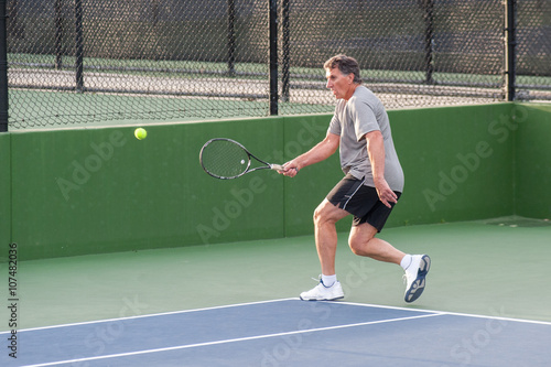 Tall Baby Boomer running to hit a wide forehand. 