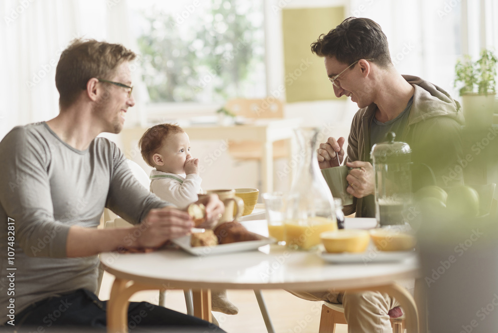 Caucasian gay fathers and baby eating breakfast Caucasian gay fathers and baby eating breakfast
