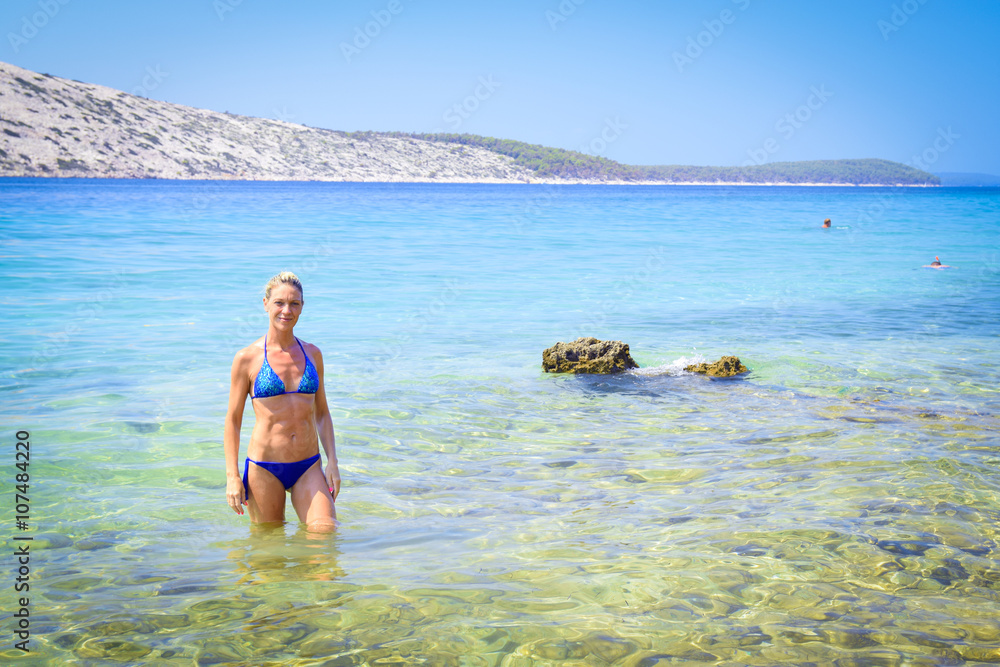 Blonde woman in blue bikini in the crystal clear waters of the s