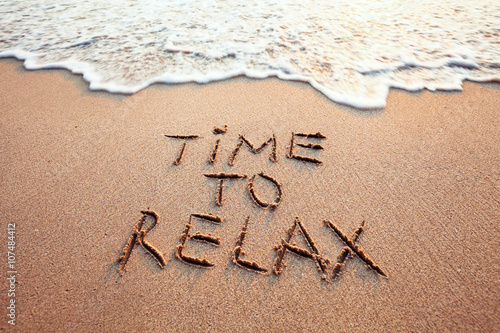 time to relax, concept written on sandy beach