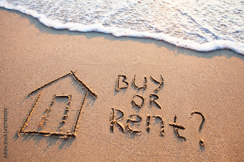 buy or rent concept, text on the sand, real estate photo