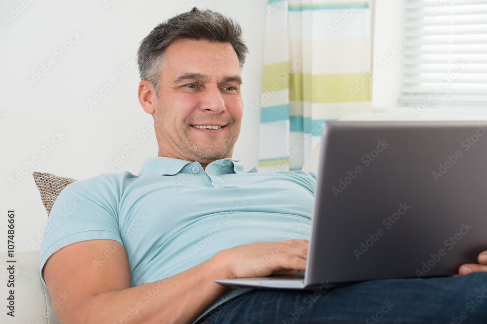 Man Lying On Sofa Using Laptop Man Lying On Sofa Using Laptop